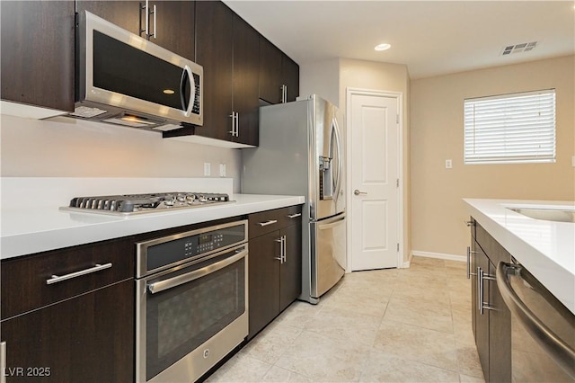 kitchen featuring stainless steel appliances, light countertops, visible vents, and dark brown cabinetry