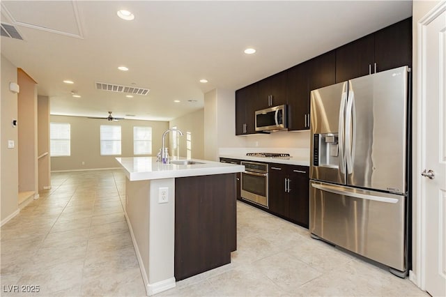 kitchen with a center island with sink, light countertops, visible vents, appliances with stainless steel finishes, and a sink