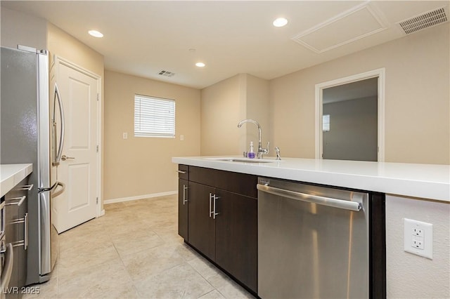 kitchen featuring stainless steel appliances, light countertops, visible vents, a sink, and dark brown cabinets