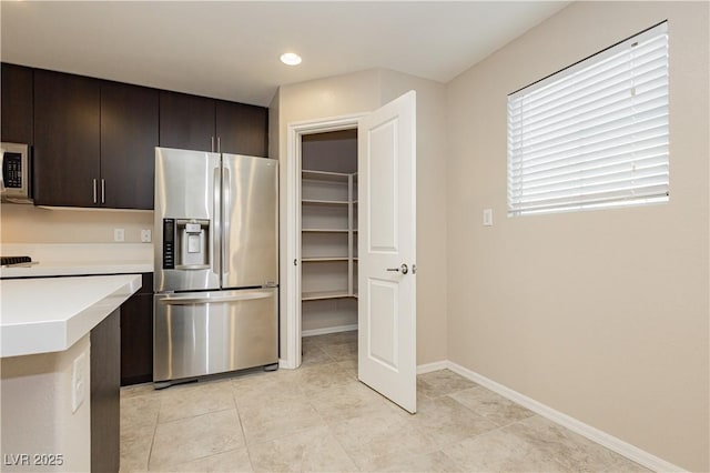 kitchen featuring dark brown cabinetry, baseboards, stainless steel appliances, light countertops, and light tile patterned flooring