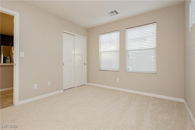 unfurnished bedroom with a closet, carpet flooring, visible vents, and baseboards