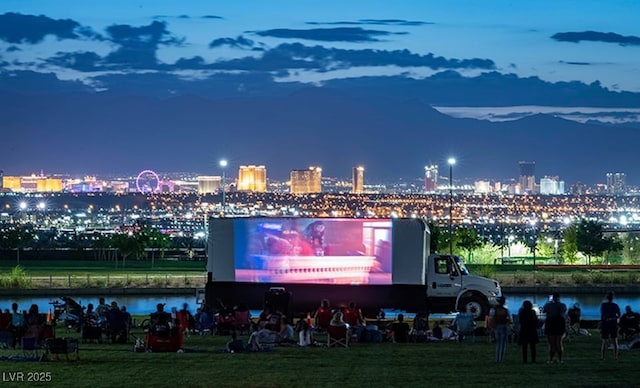 exterior space featuring a yard, a view of city lights, and a water view