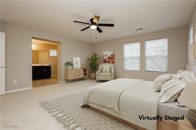 bedroom featuring light colored carpet, a ceiling fan, baseboards, visible vents, and ensuite bath