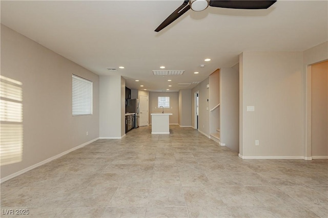 unfurnished living room with a healthy amount of sunlight, visible vents, and baseboards