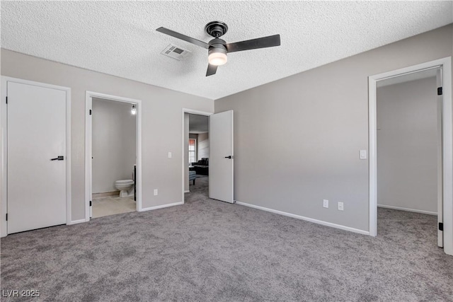 unfurnished bedroom featuring ceiling fan, a walk in closet, light colored carpet, and connected bathroom