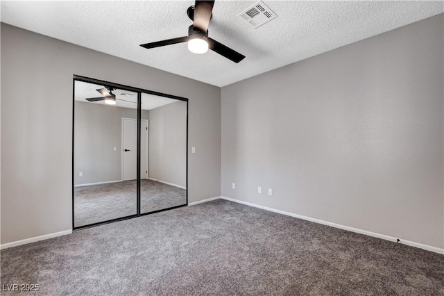 unfurnished bedroom featuring a textured ceiling, ceiling fan, a closet, and carpet floors