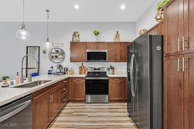 kitchen featuring sink, light wood-type flooring, pendant lighting, and appliances with stainless steel finishes