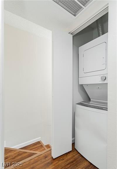 washroom with wood-type flooring and stacked washing maching and dryer