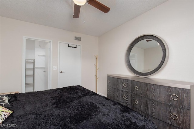 unfurnished bedroom featuring ceiling fan, a spacious closet, and a textured ceiling