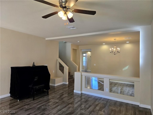 unfurnished room with ceiling fan with notable chandelier and dark hardwood / wood-style flooring