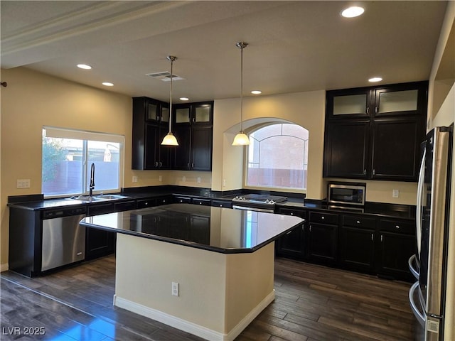 kitchen featuring a center island, dark wood-type flooring, stainless steel appliances, sink, and hanging light fixtures