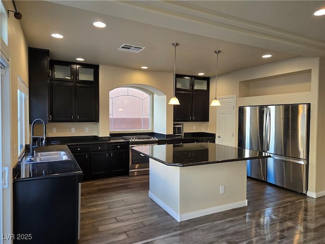 kitchen featuring a kitchen island, decorative light fixtures, stainless steel appliances, sink, and dark hardwood / wood-style floors