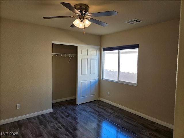 unfurnished bedroom featuring ceiling fan, a closet, and dark wood-type flooring