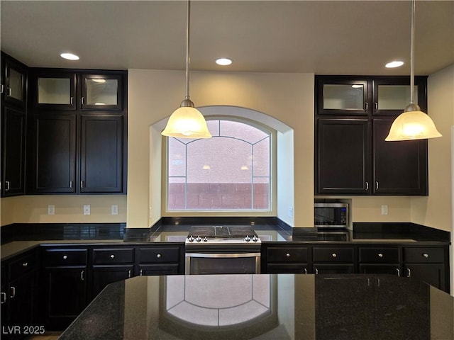 kitchen featuring hanging light fixtures, appliances with stainless steel finishes, and dark stone counters