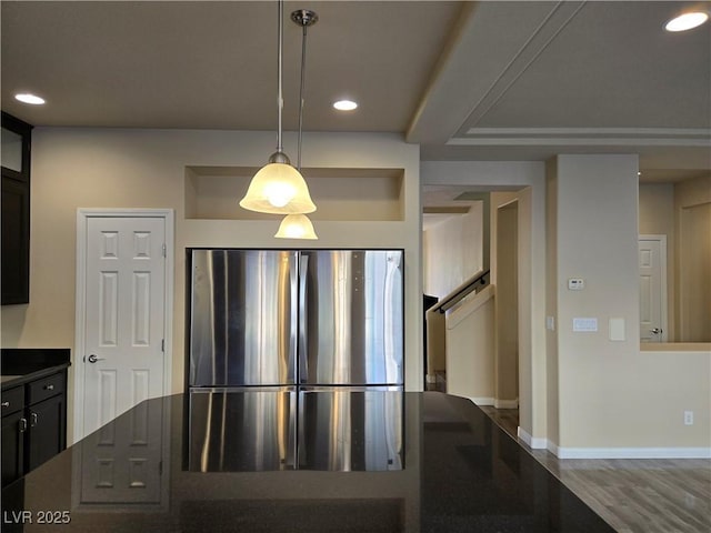 kitchen with hanging light fixtures, stainless steel refrigerator, and hardwood / wood-style flooring