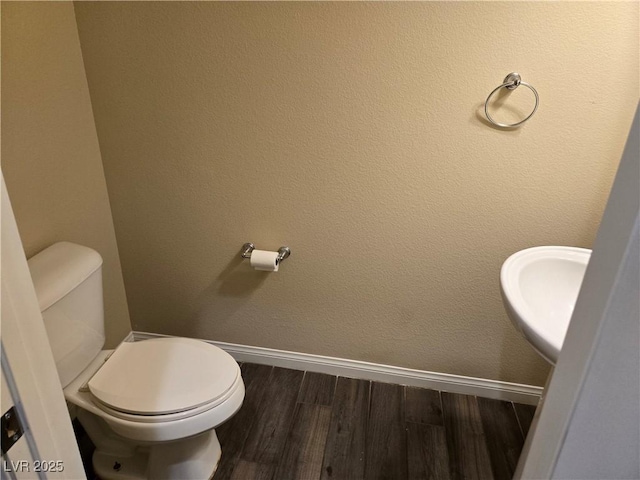 bathroom with toilet, hardwood / wood-style floors, and sink