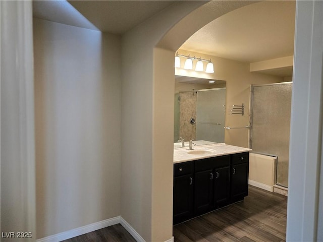 bathroom with hardwood / wood-style flooring, vanity, and an enclosed shower