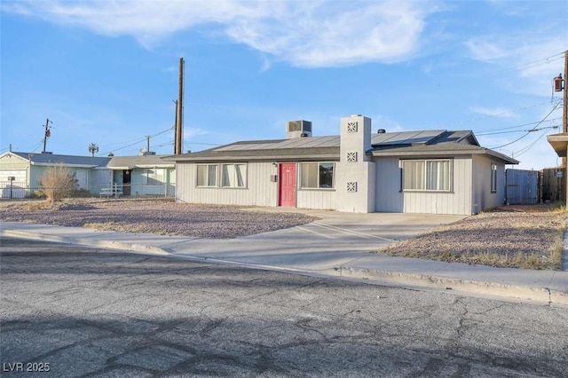 ranch-style home with cooling unit and solar panels