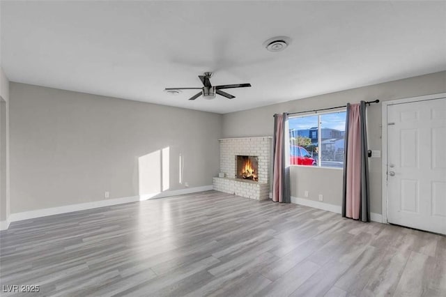 unfurnished living room with ceiling fan, light wood-type flooring, and a fireplace