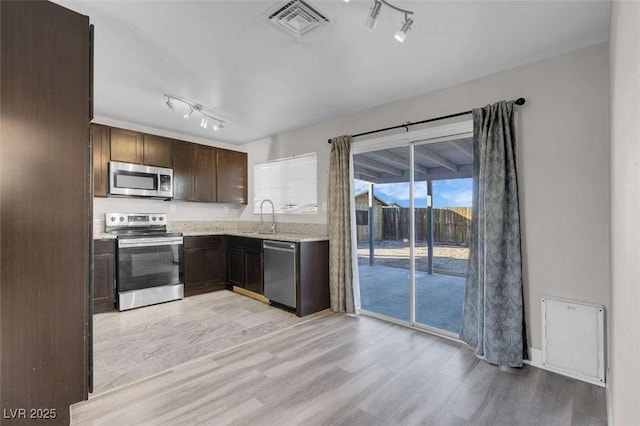 kitchen featuring dark brown cabinets, appliances with stainless steel finishes, sink, and light hardwood / wood-style flooring