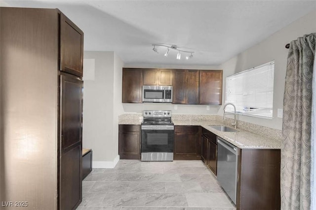 kitchen featuring light stone countertops, sink, stainless steel appliances, and dark brown cabinets