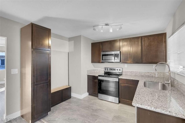 kitchen with appliances with stainless steel finishes, dark brown cabinets, light stone counters, and sink