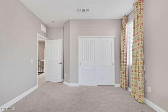 unfurnished bedroom featuring a closet and light colored carpet