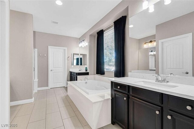 bathroom featuring tiled bath, vanity, and tile patterned flooring