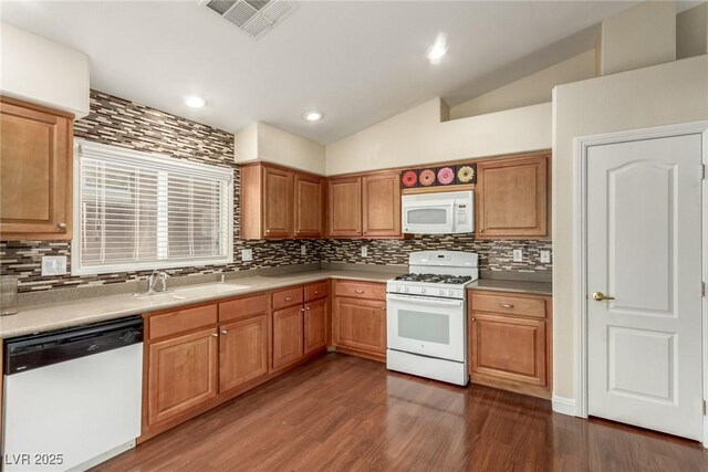 kitchen featuring lofted ceiling, dark wood-type flooring, sink, and white appliances