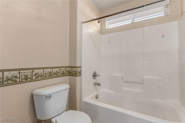 bathroom with washtub / shower combination, tile walls, and toilet