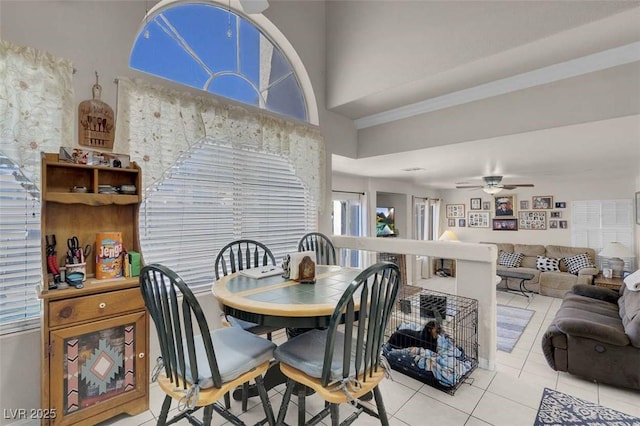 tiled dining room with ceiling fan and a towering ceiling