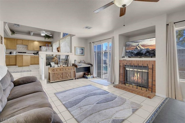 tiled living room with ceiling fan and a fireplace