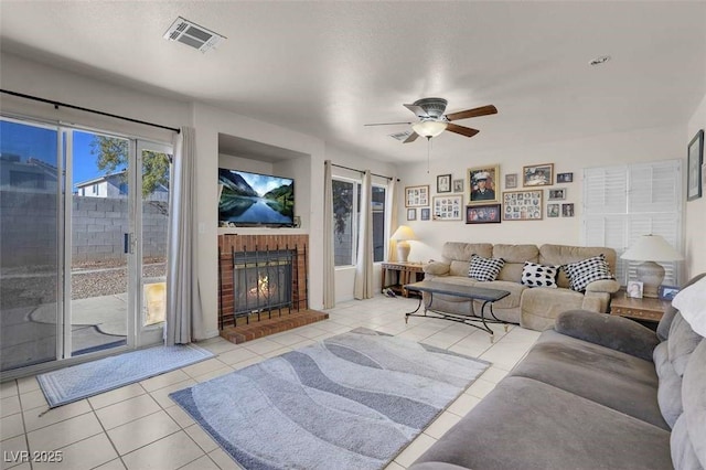 tiled living room featuring ceiling fan, a fireplace, and a textured ceiling