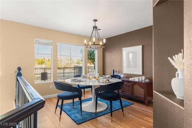 dining area with light hardwood / wood-style flooring and a chandelier