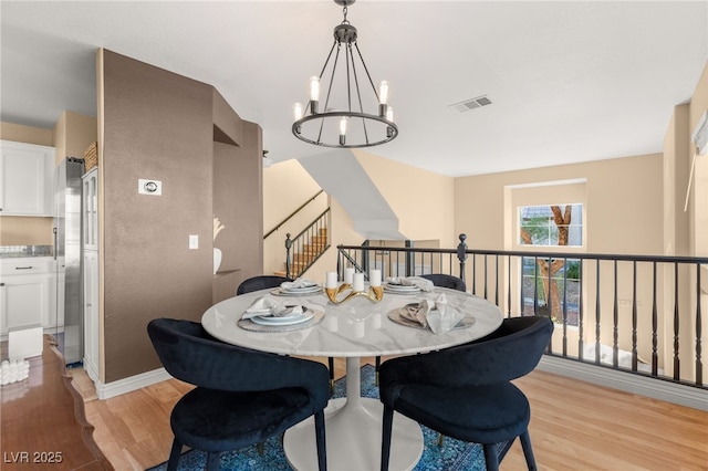 dining area with light hardwood / wood-style flooring and a chandelier