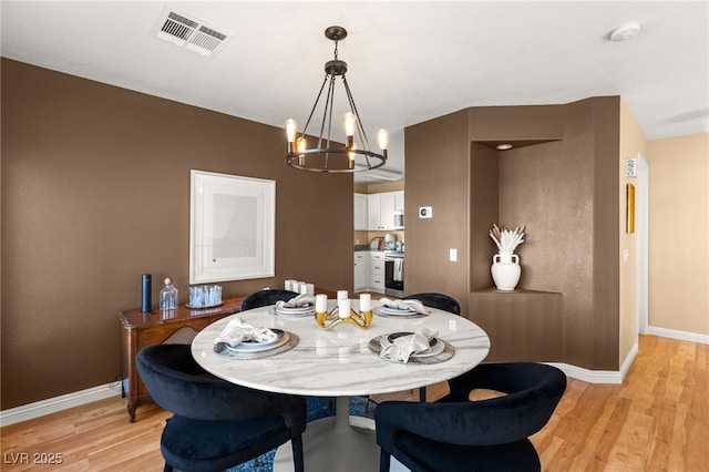 dining space featuring an inviting chandelier and light hardwood / wood-style floors