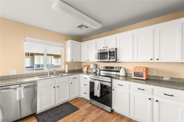 kitchen with light hardwood / wood-style floors, sink, white cabinets, and appliances with stainless steel finishes