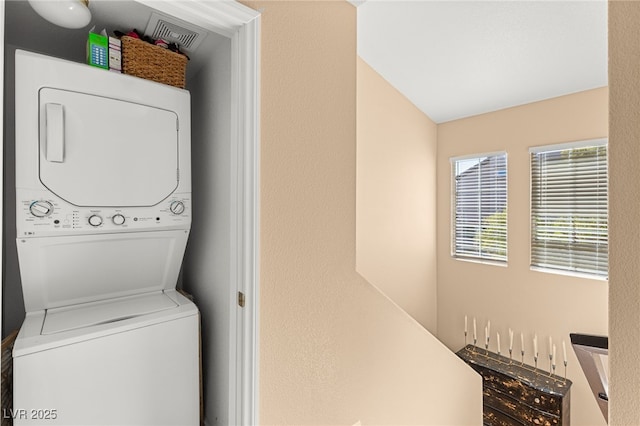 clothes washing area featuring stacked washer and dryer