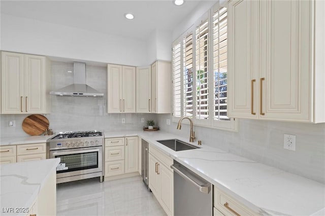 kitchen with wall chimney range hood, stainless steel appliances, tasteful backsplash, sink, and light stone counters