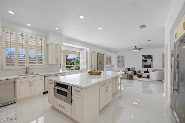 kitchen featuring tasteful backsplash, ceiling fan, a center island, sink, and stainless steel appliances