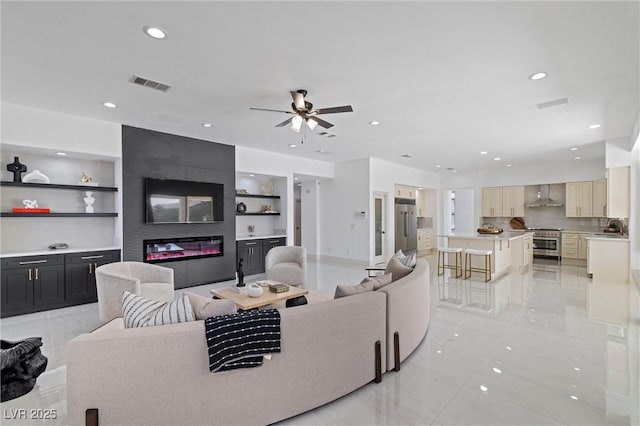 living room featuring built in features, a fireplace, and sink