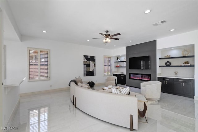 living room featuring ceiling fan, a fireplace, and built in shelves