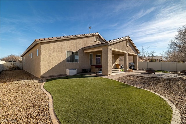 rear view of property featuring a patio, a lawn, and an outdoor fire pit