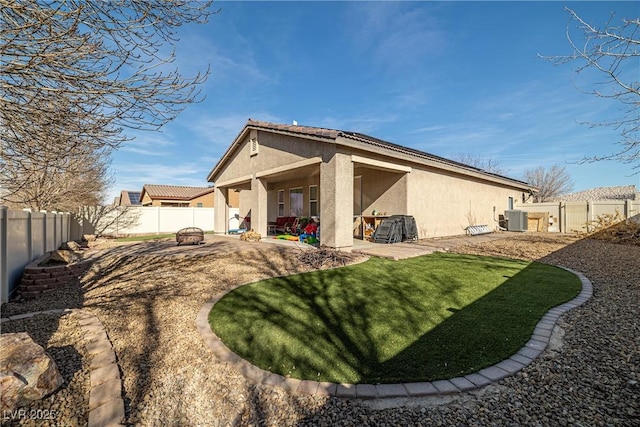 rear view of house with cooling unit, a patio, and a lawn