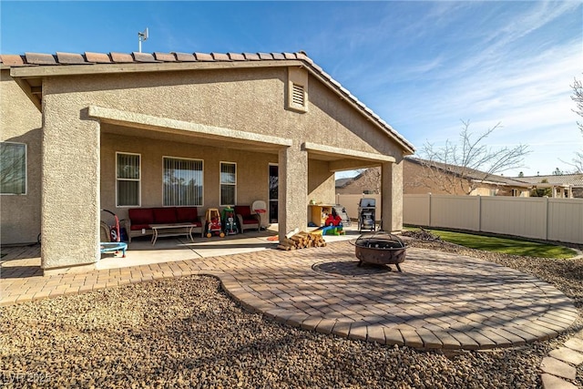 rear view of property featuring a patio and an outdoor fire pit