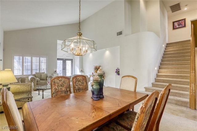 dining room featuring high vaulted ceiling, a chandelier, and french doors