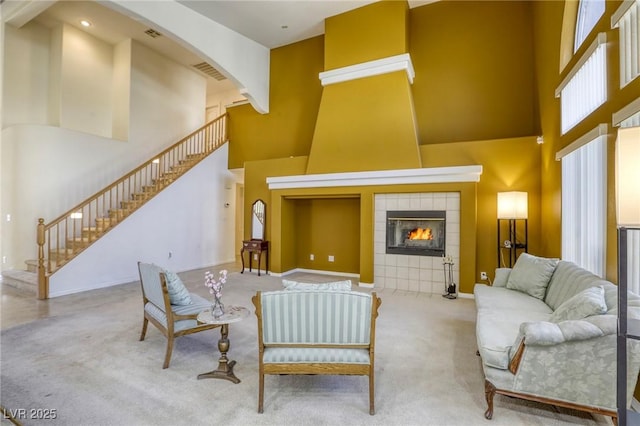 carpeted living room featuring a towering ceiling and a tile fireplace