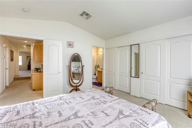 carpeted bedroom featuring multiple closets, ensuite bath, and vaulted ceiling