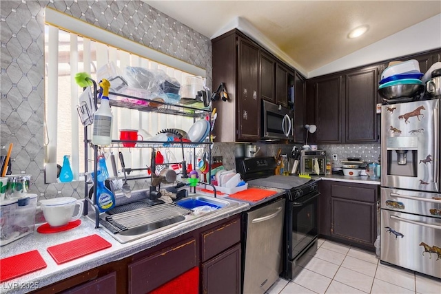 kitchen featuring lofted ceiling, sink, light tile patterned flooring, stainless steel appliances, and dark brown cabinets