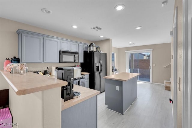 kitchen with kitchen peninsula, gray cabinets, stainless steel refrigerator with ice dispenser, range, and light hardwood / wood-style flooring